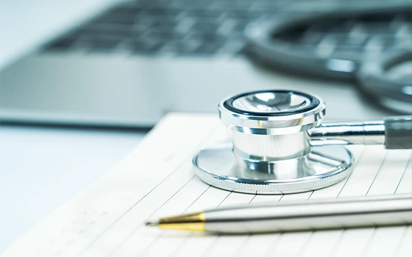 Stethoscope, pen and laptop